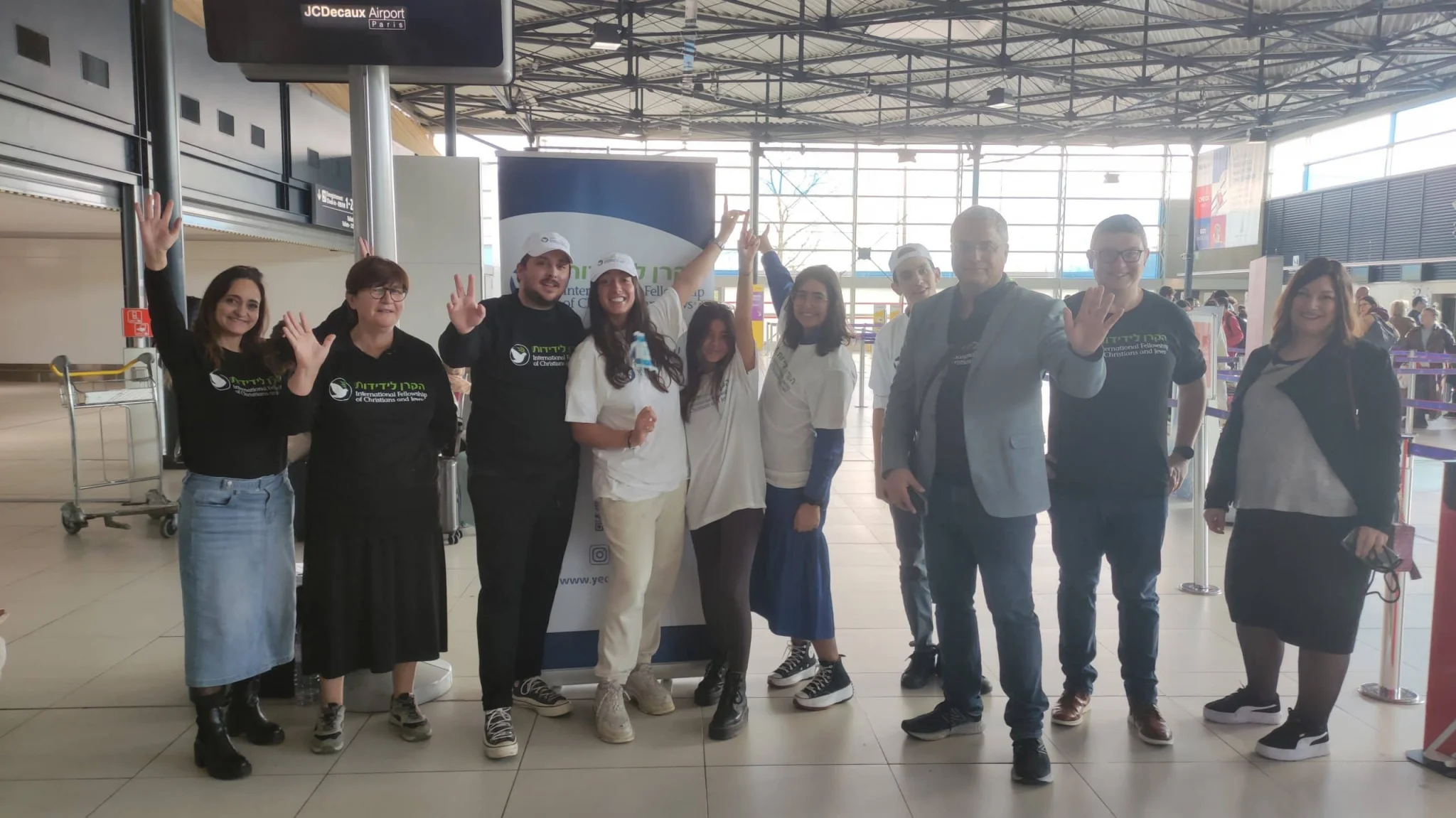 Équipe de la Keren Layedidout à l’aéroport, saluant joyeusement avant un vol d’aide humanitaire.